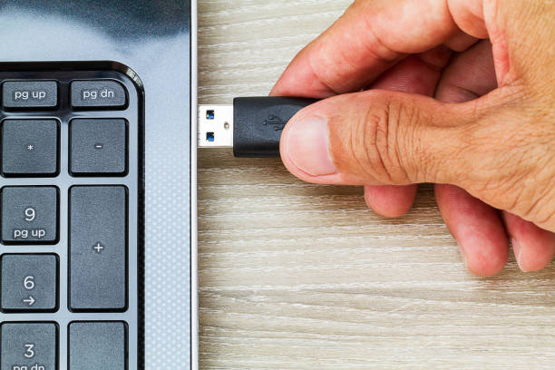 Hand connecting USB cable to laptop computer on wooden desk Hand connecting USB cable to laptop computer on wooden desk external hard disk drive stock pictures, royalty-free photos & images