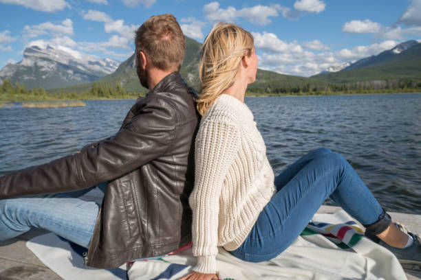 istock Two young adults sitting on lake pier 844088384