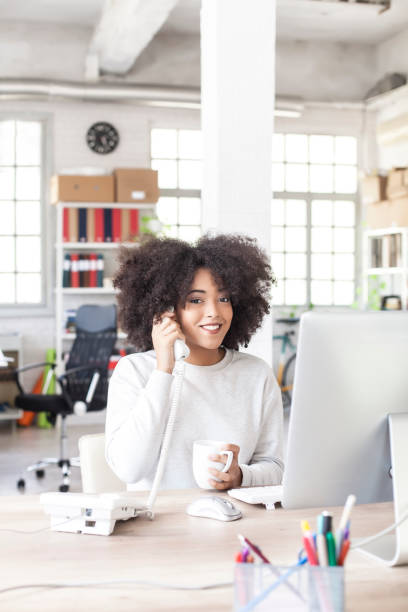istock Smiling female assistant using landline phone in modern office 844098976