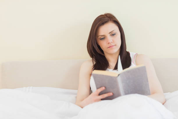 istock Concentrated girl reading a book lying on a bed 844136368