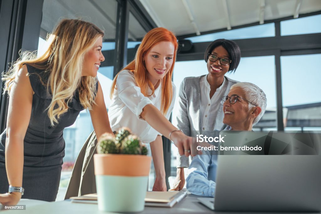 Working on a new project Team of businesswomen working on a laptop in a cafe. Leadership Stock Photo