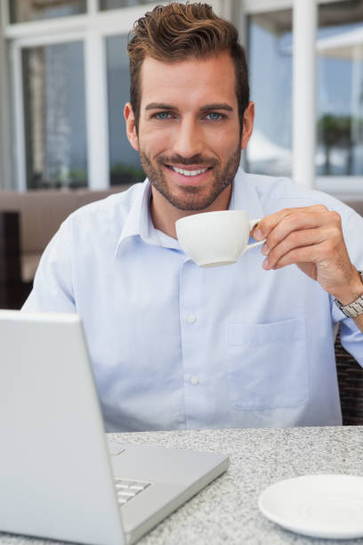istock Smiling businessman working with laptop drinking coffee 844147944