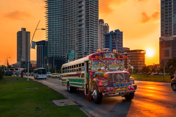 Red Devil bus in Panama City with modern building on the background at sunset, in Panama. Panama City, Panama - March 18, 2014: A Red Devil bus in Panama City with modern building on the background at sunset, in Panama. panama city panama stock pictures, royalty-free photos & images