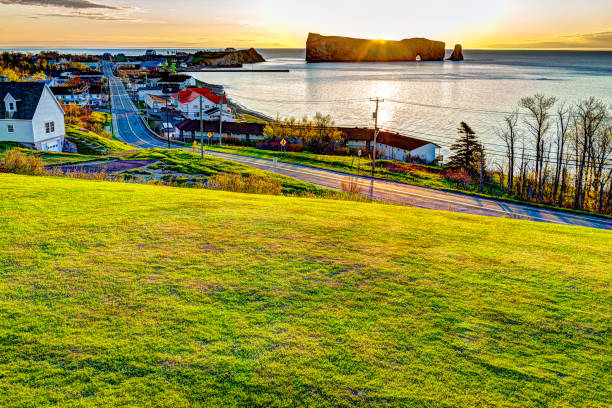 Famous Rocher Perce rock in Gaspe Peninsula, Quebec, Canada, Gaspesie region with cityscape at sunrise and sun Famous Rocher Perce rock in Gaspe Peninsula, Quebec, Canada, Gaspesie region with cityscape at sunrise and sun gaspe peninsula stock pictures, royalty-free photos & images