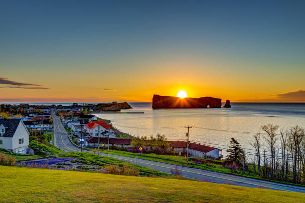 Famous Rocher Perce rock in Gaspe Peninsula, Quebec, Canada, Gaspesie region with cityscape at sunrise and sun Famous Rocher Perce rock in Gaspe Peninsula, Quebec, Canada, Gaspesie region with cityscape at sunrise and sun gaspe peninsula stock pictures, royalty-free photos & images