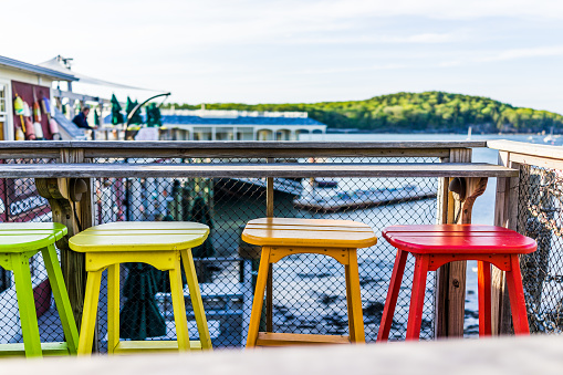 Colorful vivid chairs painted green, yellow and orange on waterfront bar restaurant