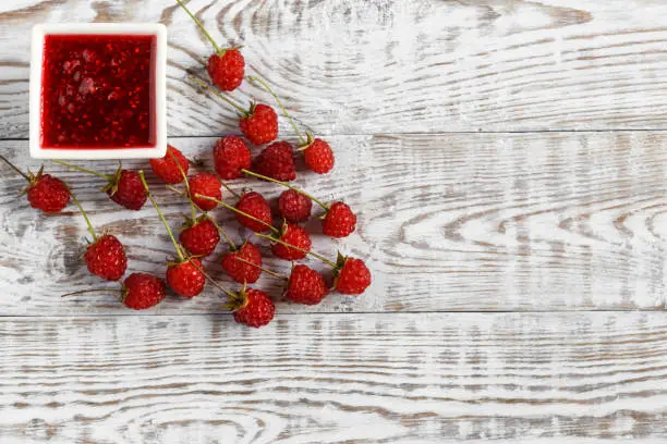 Fresh raspberry and raspberry jam on a wooden background. Copy space