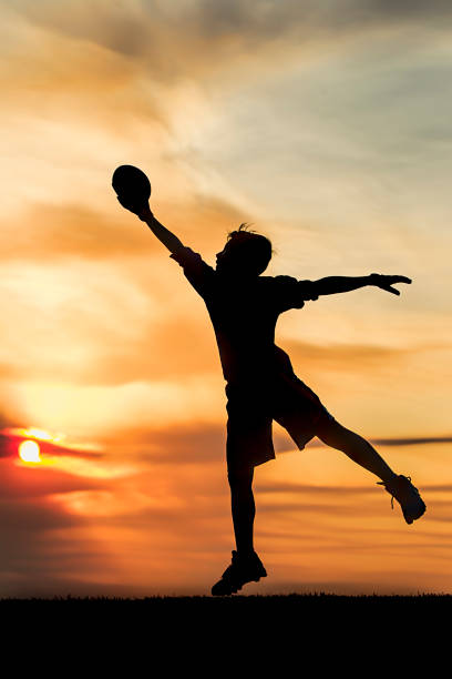 istock Boy leaping for the football at sunset. 844174166