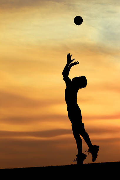 istock Silhouette of boy leaping for ball. 844174168