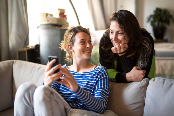 istock People relations. Two girls are speaking and using cellphone on sofa 844183362