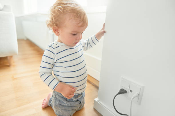 Baby boy looking at electrical plug in the wall.