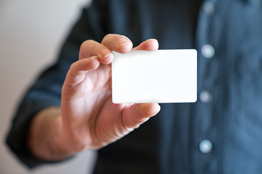 Mano sosteniendo la vista de frente de maqueta de blanco en blanco de la tarjeta de crédito. Diseño plástico de la tarjeta de banco imitan para arriba photo