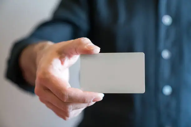 Hand holding blank white credit card mockup front side view. Plastic bank-card design mock up