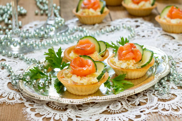 weihnachten-snack auf dem festlich gedeckten tisch. törtchen mit salat, dekoration aus lachs und gurke. - 7676 stock-fotos und bilder