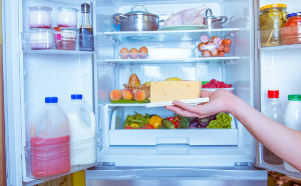 istock Open refrigerator filled with food. Man holding cheese 844197120