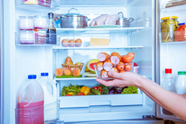 istock Open refrigerator filled with food.hands holding sausage 844198672