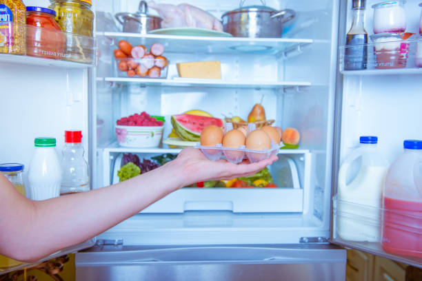 istock Open refrigerator filled with food. hands holding a box with eggs 844199596