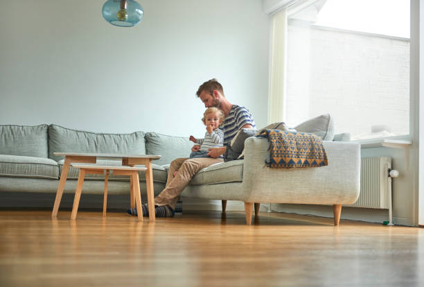 Father and son on couch. Putting on clothes