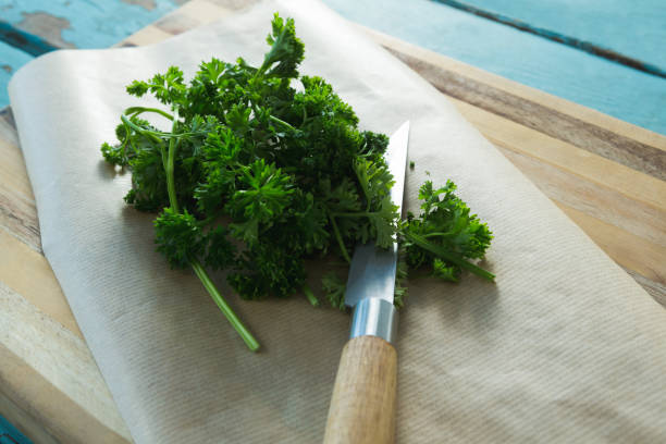 istock Coriander leaves, wax paper and knife on chopping board 844223324
