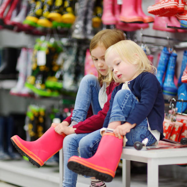 istock Two sisters choosing and trying on new rain boots 844229604
