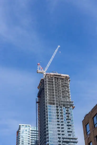 construction site with a white crane on top of an office or apartment tower in Toronto that has a glass front