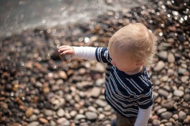 un ragazzo che lancia una roccia vicino a un fiume - throwing stone human hand rock foto e immagini stock