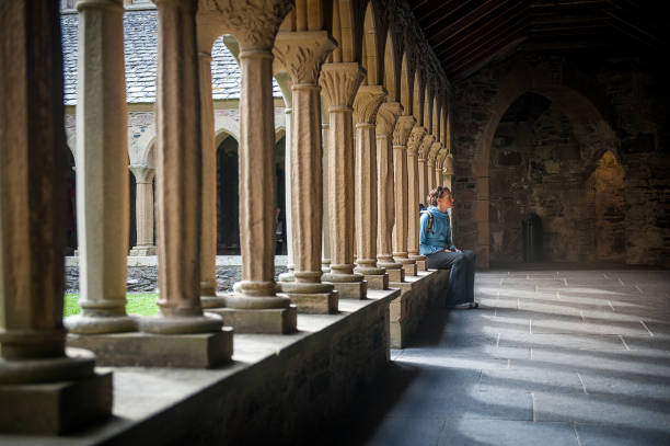 Female sitting between pillar of Iona Monastery