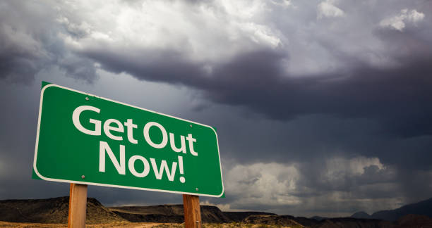 istock Get Out Green Road Sign and Stormy Clouds 844265076
