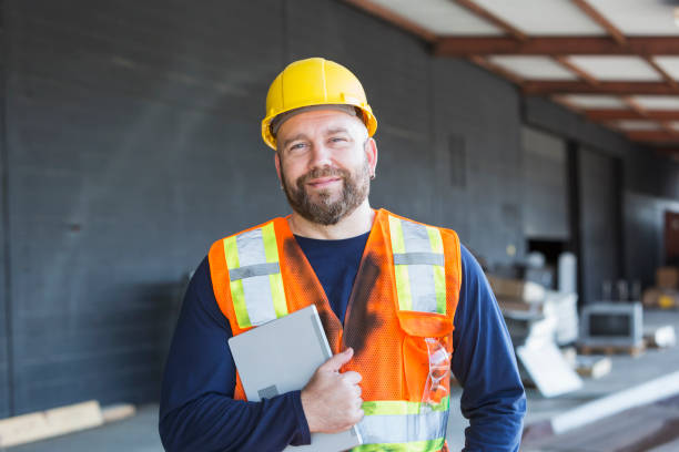 istock Worker in safety vest and hardhat holding digital tablet 844271918