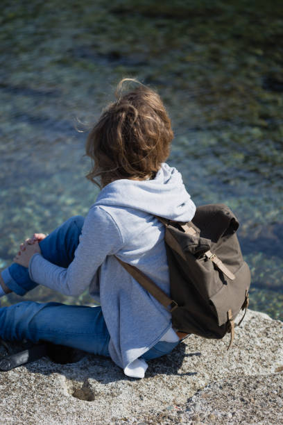 istock Woman tourist with camera and backpack sitting and relaxing on s 844271940