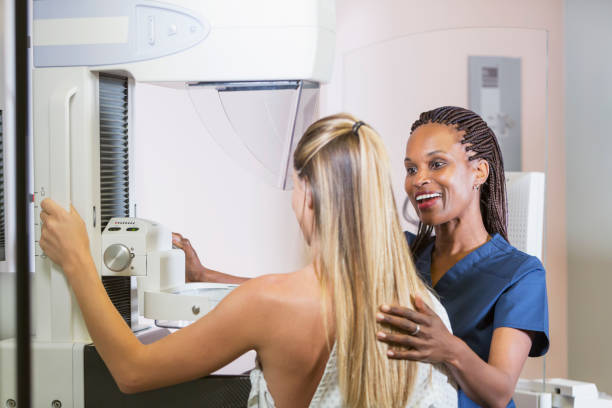 Woman getting mammogram A mid adult woman getting a mammogram. She is being helped by an African-American nurse. x ray image medical occupation technician nurse stock pictures, royalty-free photos & images