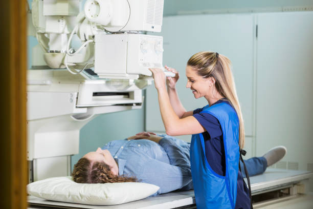 Technician with patient getting x-ray A medical professional with a female patient who is lying on her back getting an x-ray. x ray image medical occupation technician nurse stock pictures, royalty-free photos & images