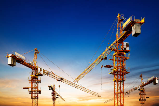 istock Industrial construction cranes and building silhouettes over sun at sunrise. 844277914