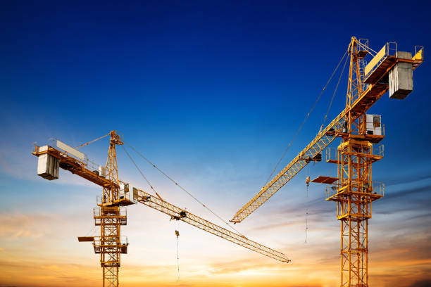 gru da costruzione industriali e sagome di edifici sopra il sole all'alba. - crane foto e immagini stock