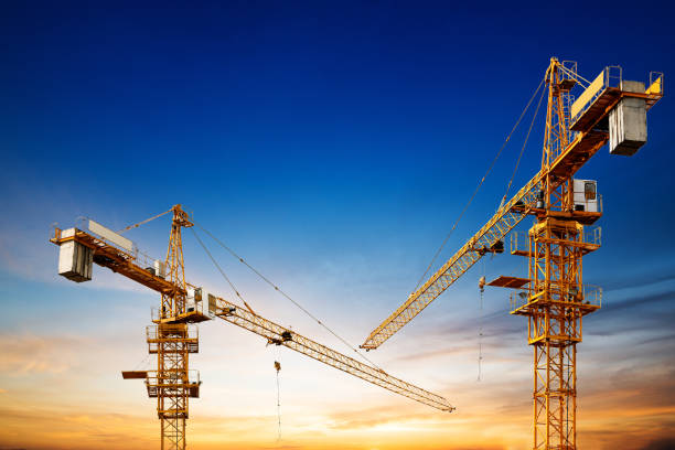 Industrial construction cranes and building silhouettes over sun at sunrise. stock photo