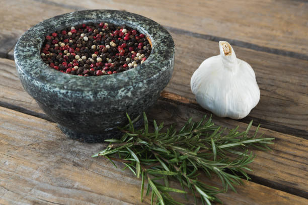 Close-up of garlics, rosemary and mix peppercorns on chopping board