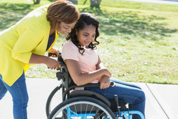 mère avec une fille adolescente en fauteuil roulant - disabled teenager adolescence physical impairment photos et images de collection
