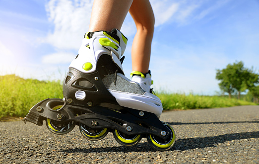 Female legs in inline skates in action outdoors on sunny day.