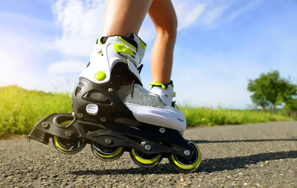 Female legs in inline skates in action outdoors on sunny day.