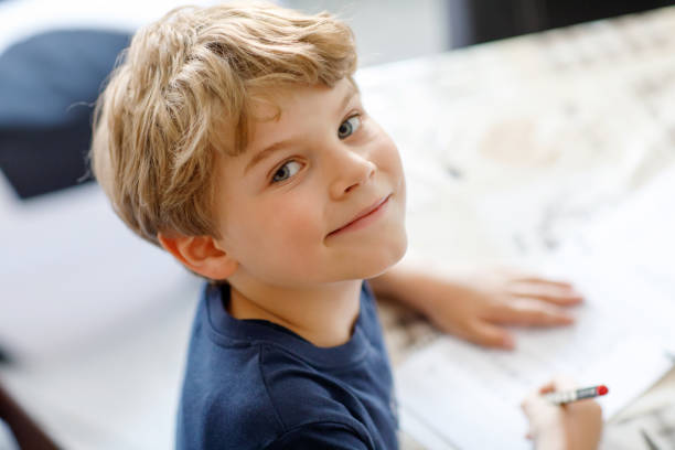 istock Happy smiling kid boy at home making homework writing letters with colorful pens 844315882