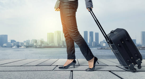 istock business woman walking by pulling a suitcase in downtown street. 844319646