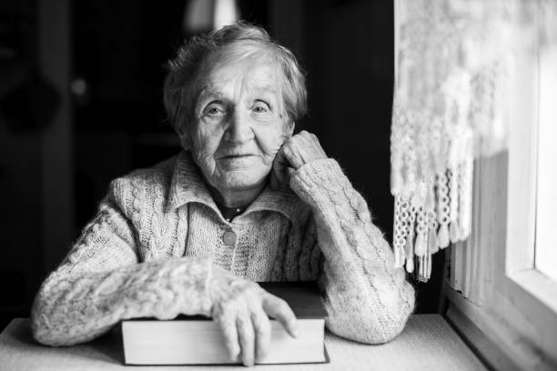 istock An elderly woman with a closed book at the table. 844322584