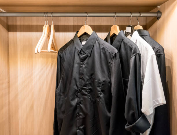 istock Black basic shirts hanging in the wooden closet. 844323230