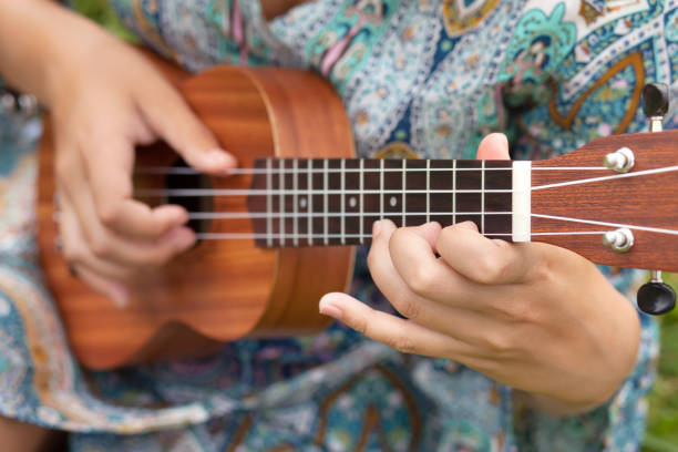 Closeup photo of young woman playing on Ukulel. Young hipster woman playing on Ukulele outdoors. ukulele stock pictures, royalty-free photos & images