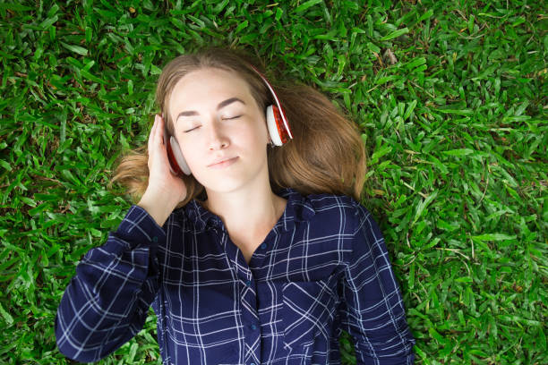 istock Content Young Lady Listening to Music on Grass 844347294