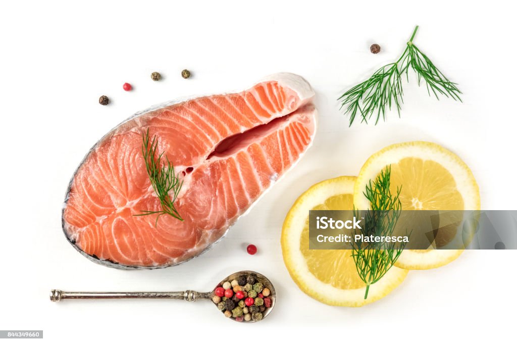 Salmon steak with lemons, dill, and peppercorns, on white An overhead photo of a raw salmon steak with dill, lemons, and peppercorns, shot from above on a white background with a place for text Fish Stock Photo