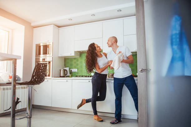 istock Beautiful young couple is talking, looking at camera and smiling while cooking in kitchen. 844350684