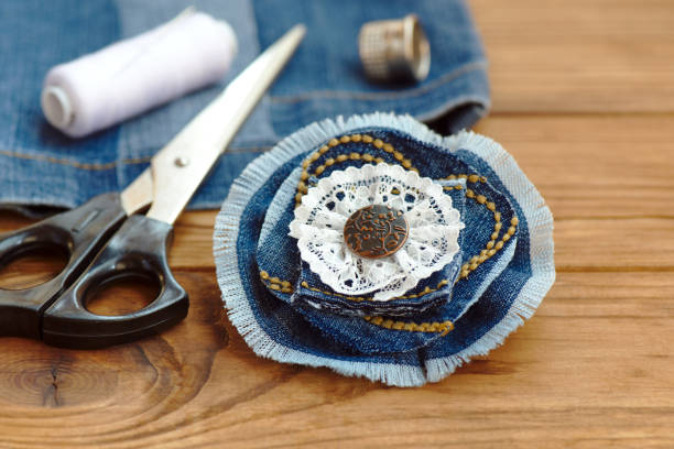 Jewelry made from denim. Cheap raft ideas to sell. Cheap arts and crafts ideas for adults. Recycle jeans. Dnim jewelry tutorial. What to do with old blue jeans. Recycled denim fabric crafts. Denim recycling idea. What to do with torn jeans broche de la flor azul del dril de algodón o pelo accesorio. tijeras, hilo, dedal, aguja, viejos jeans en una mesa de madera. tela del dril de algodón reciclado. creativo utiliza pantalones vaqueros viejos. idea de arte casero barato. closeup