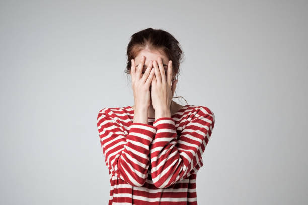 Pretty caucasian girl covers her face with her hands Pretty caucasian girl covers her face with her hands, feel embarrassed or shy. shy stock pictures, royalty-free photos & images