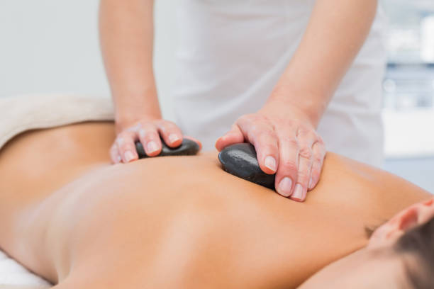 piękna kobieta otrzymująca masaż kamienia w centrum spa - massage therapist lastone therapy massaging spa treatment zdjęcia i obrazy z banku zdjęć